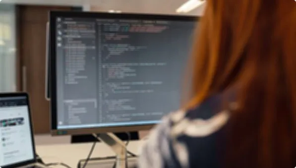 Desenvolvedora acompanhando código em monitor de alta resolução